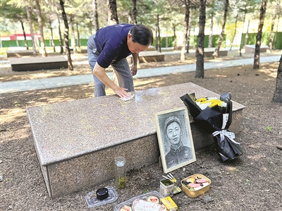 胡繼明為父親擦拭墓碑。劉陽陽攝