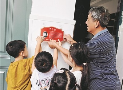 蔣賢禮烈士的兒子蔣義生，與楂林小學“賢禮班”學生一起掛“英烈牌”。季俊磊攝