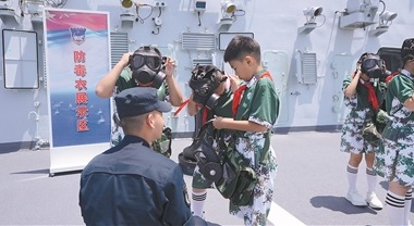 河北省石家莊市華夏小學學生在海軍石家莊艦上體驗穿戴防護設備。李鳳祥 攝